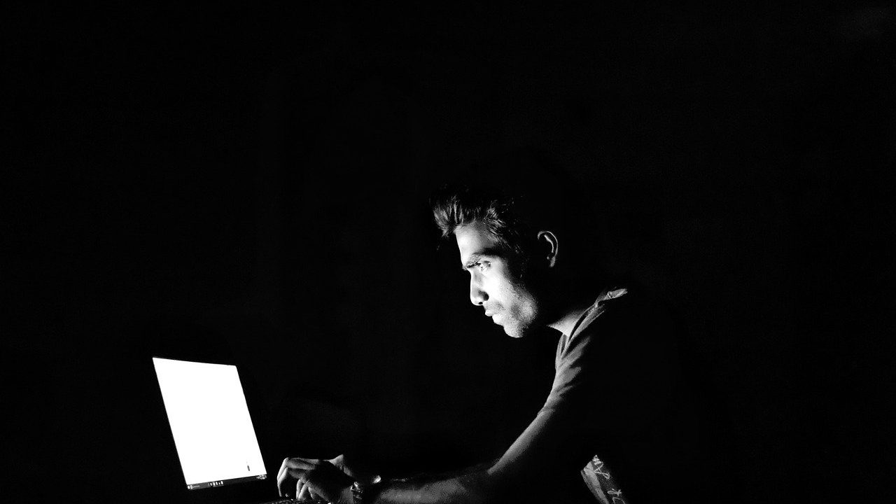 暗い部屋でパソコンを見ている男性